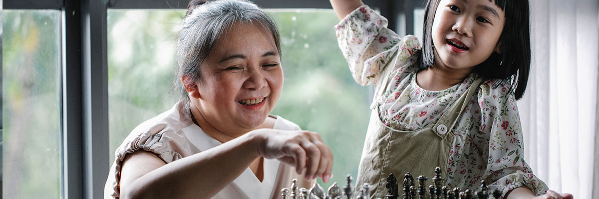 A grandmother and her granddaughter playing chess together.