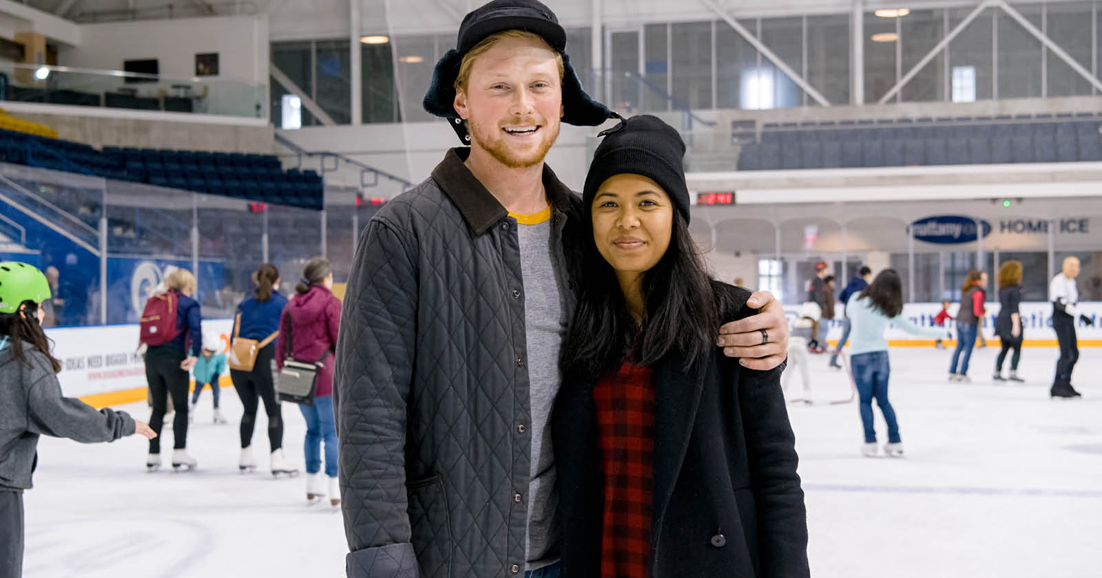 Two TMU community members posing for a photo while skating on the ice at the MAC
