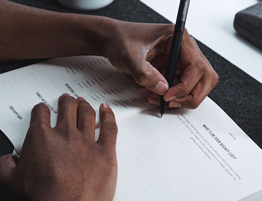 Hand holding pencil, making entry into a journal 