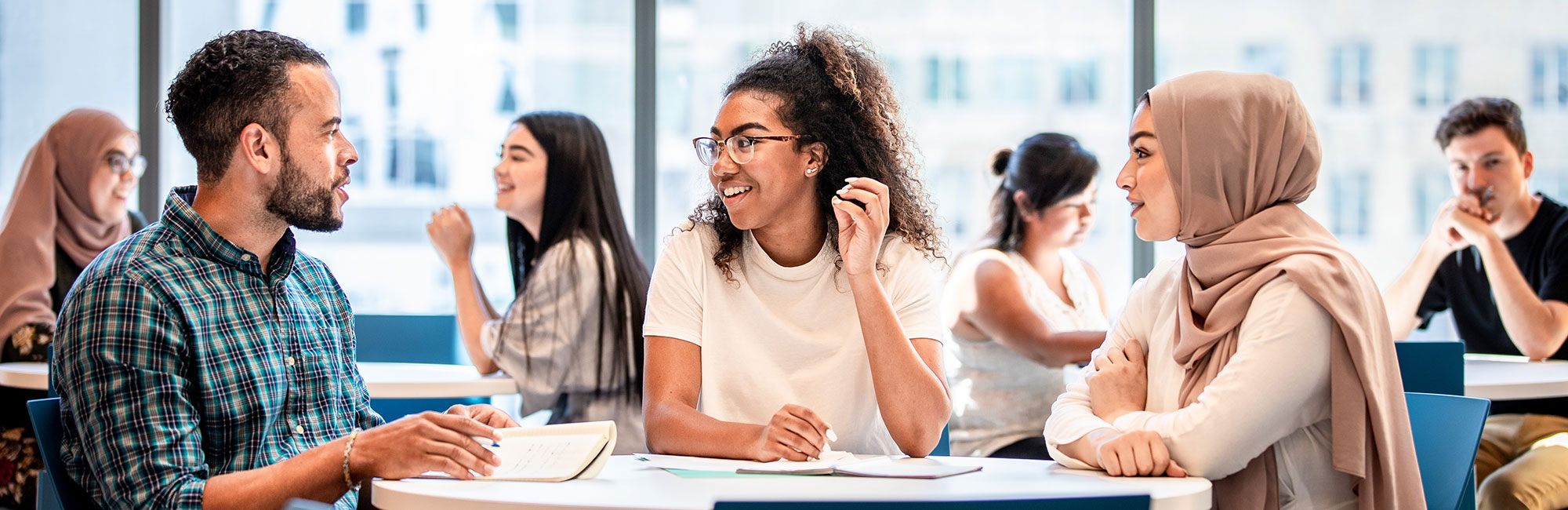 Three TMU community members sitting at a table having a conversation.