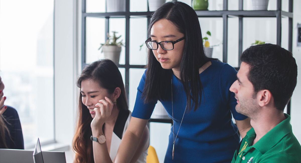 Des étudiants travaillent en collaboration debout et assis devant un ordinateur