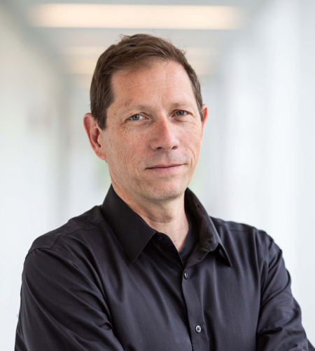 Ted Hiebert with a neutral expression. He is wearing a dark grey button up shirt and has short brown hair.