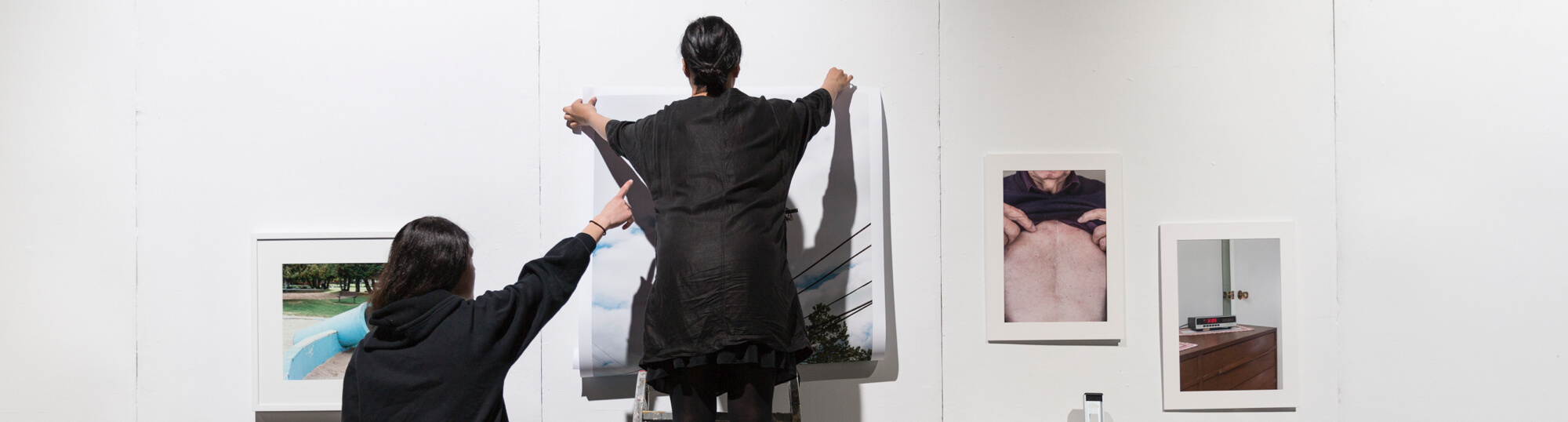 Two students hangning photos in a gallery