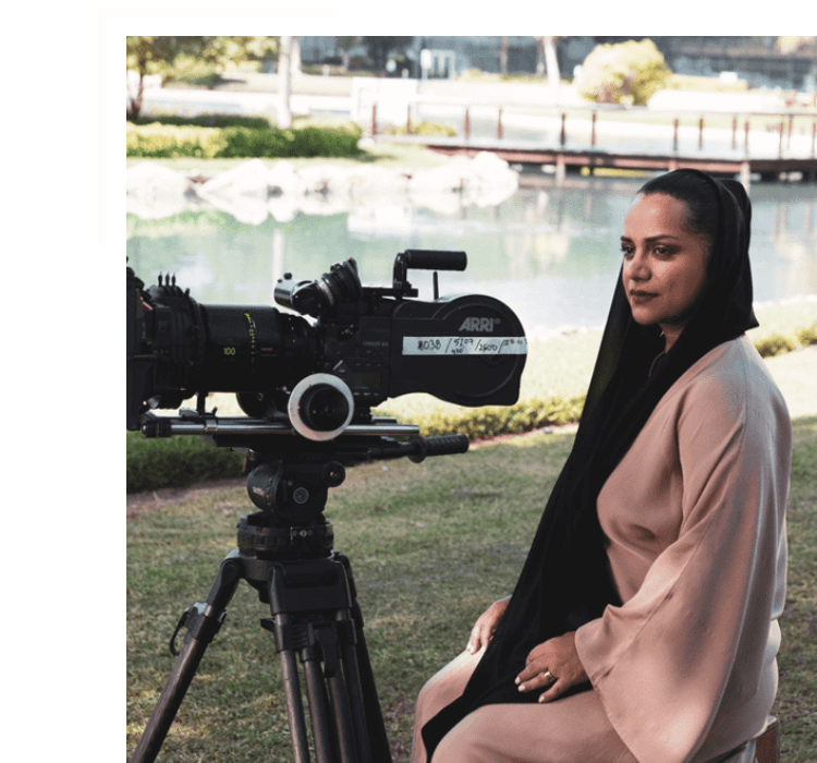Filmaker Nayla Al Khaja sitting behind film camera on set