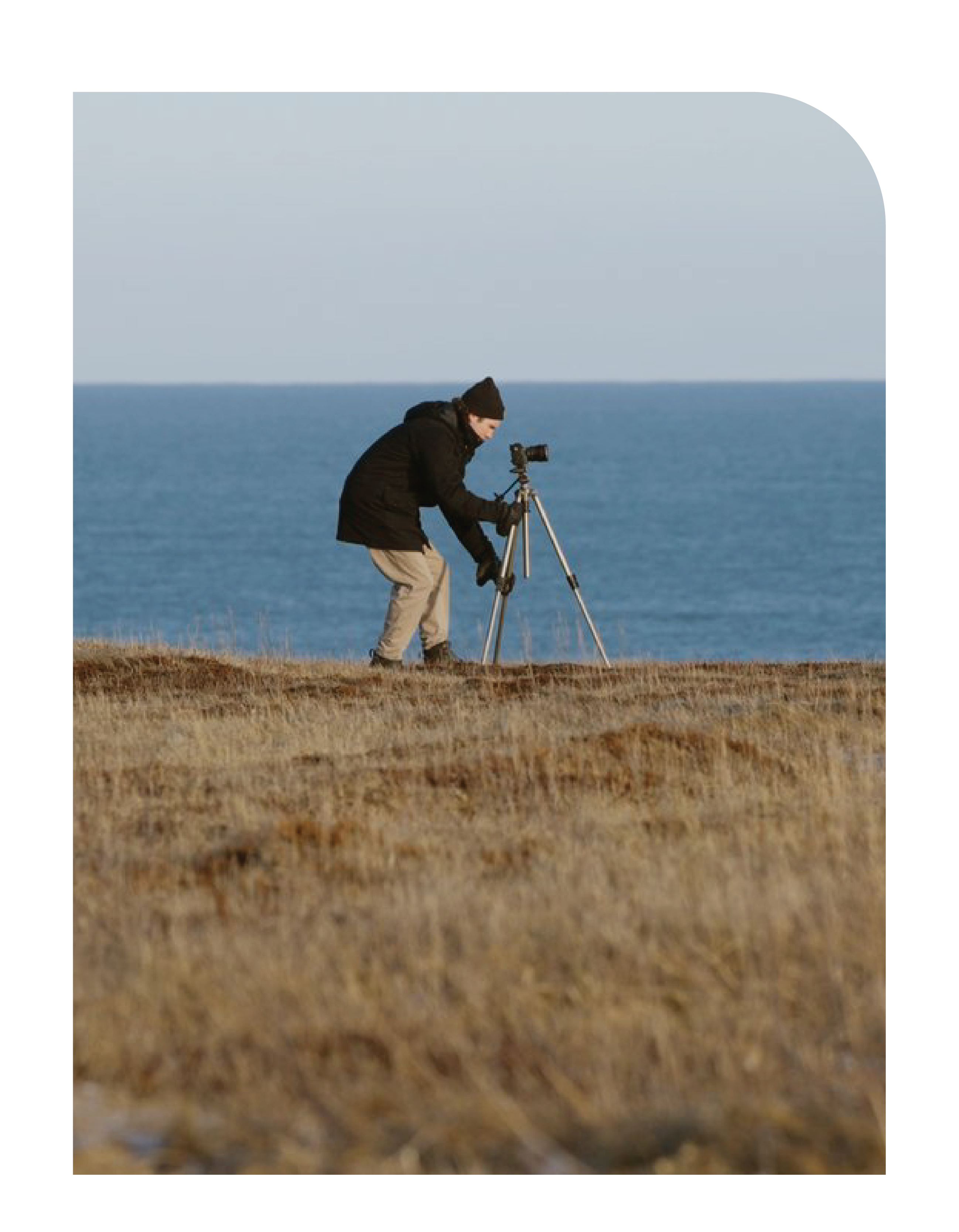 Photography student setting up tripod near the ocean