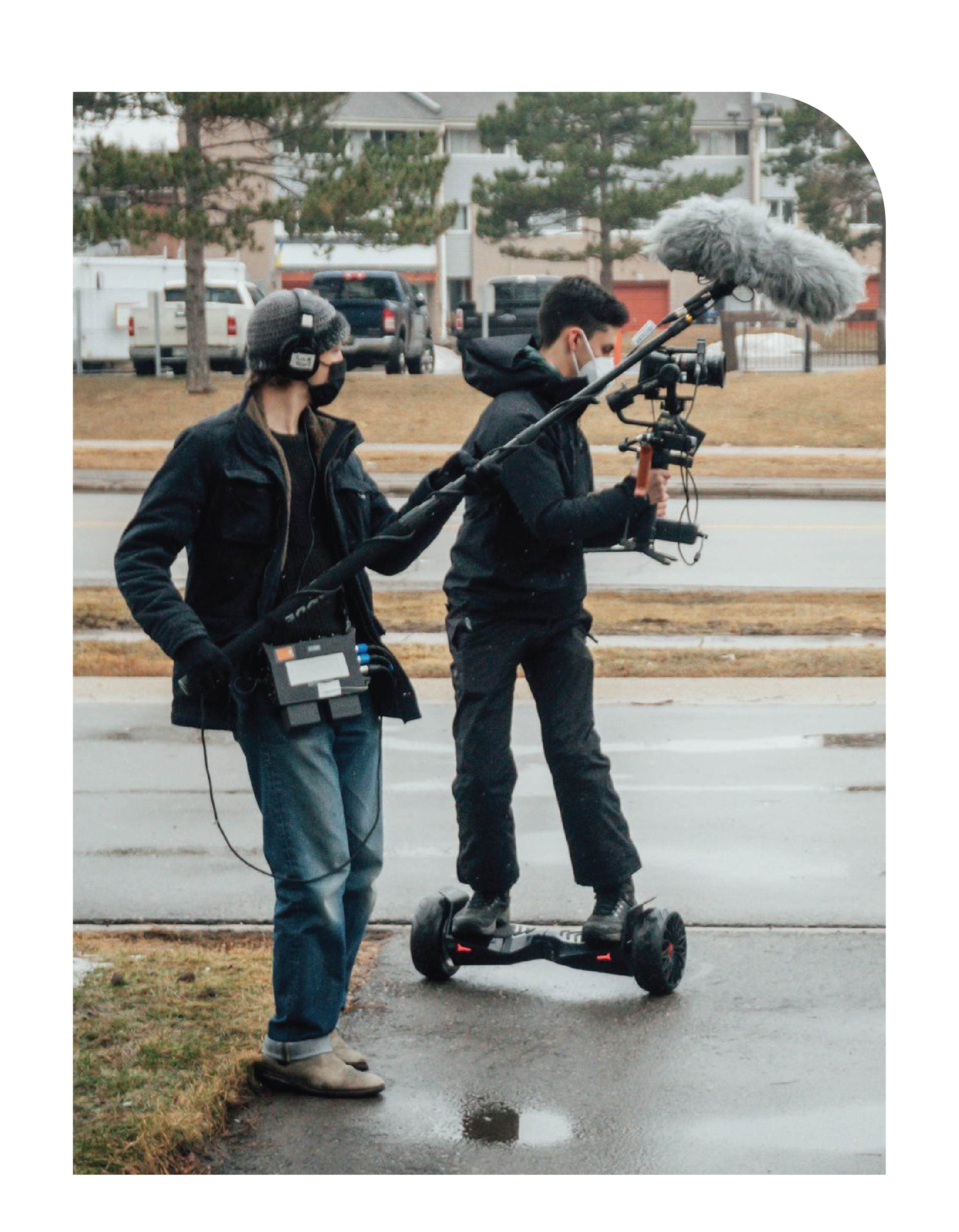 Two students on film shoot: one holding boom mic, the other shooting with camera