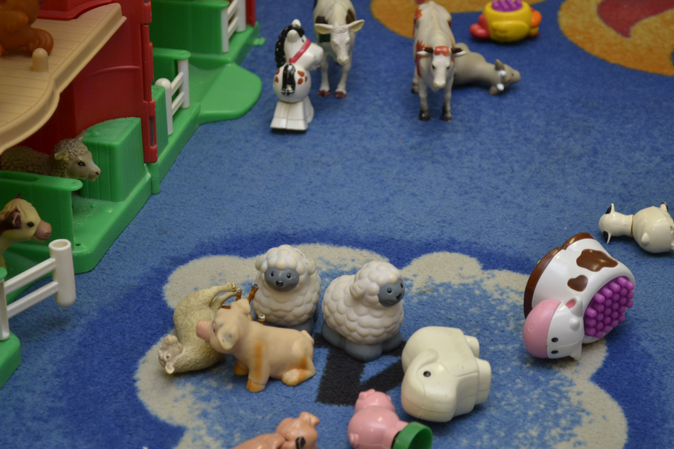 Various plastic toys for children on the carpeted floor of a childcare centre. 