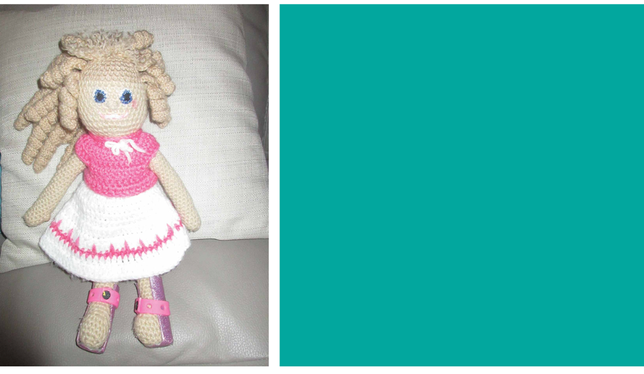 A handmade doll with a pink and white dress and pink braces on her legs