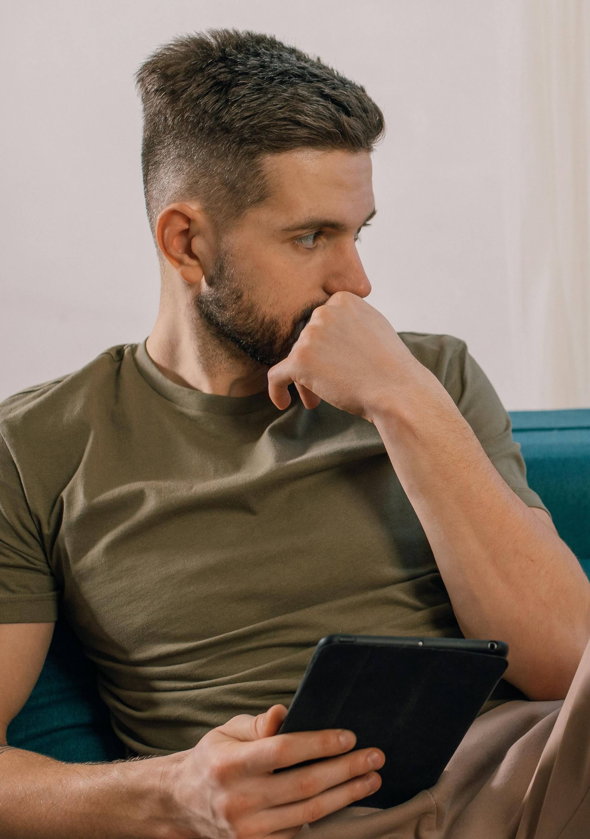 Man looking contemplative, holding tablet
