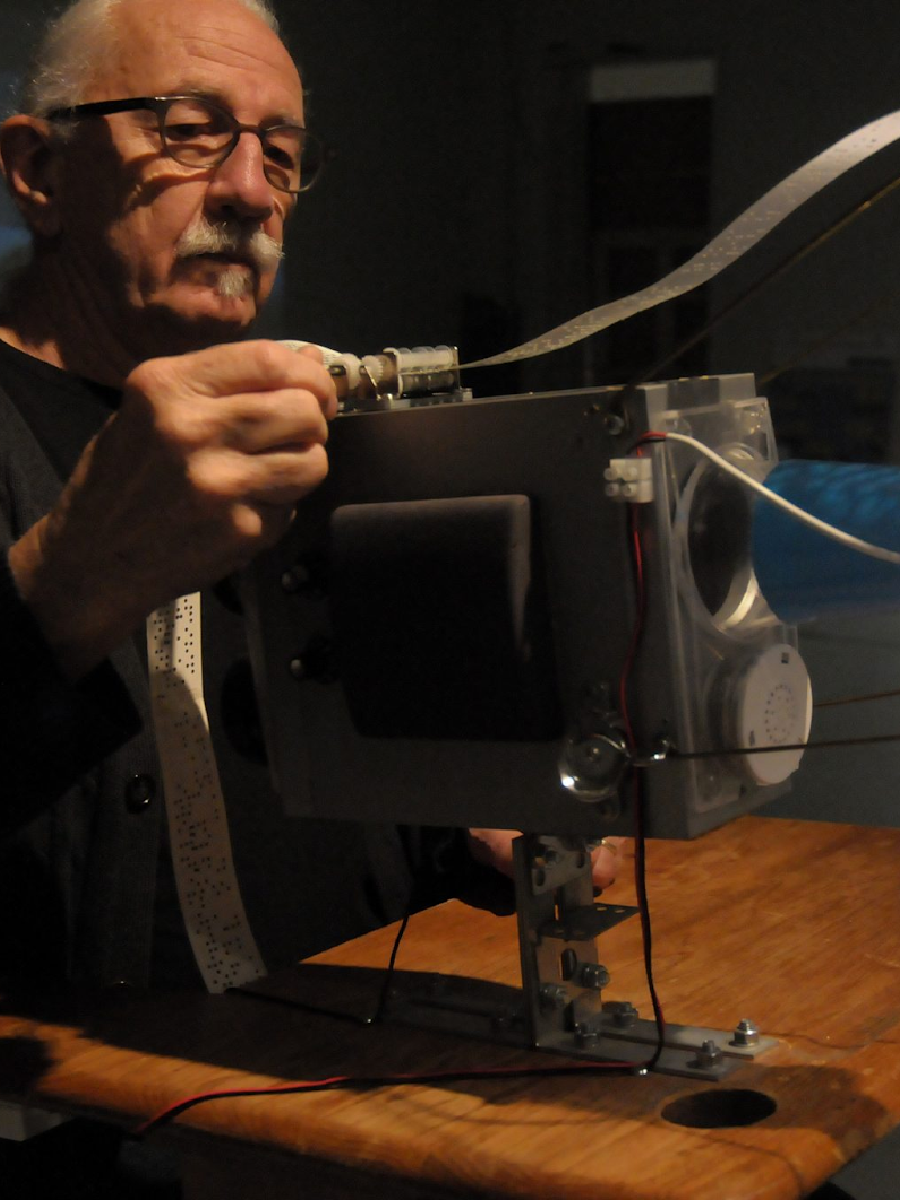 Artist David Bobier feeding in a Braille paper strip into projector like equipment 