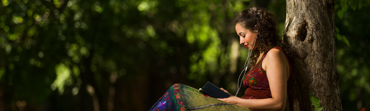 Someone sitting by a tree using their mobile