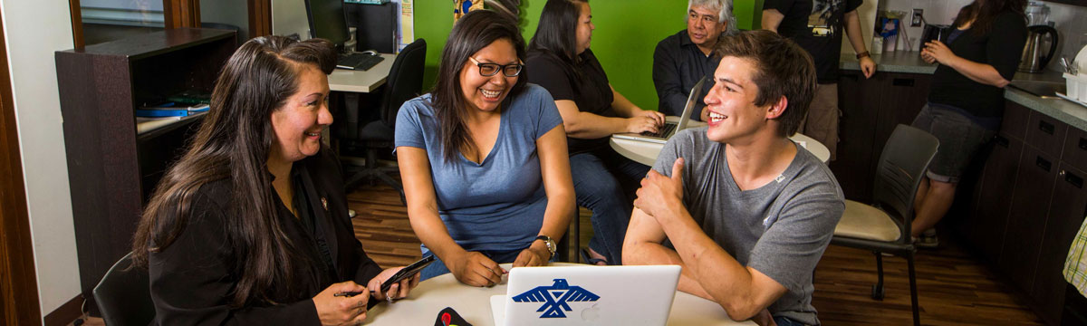 Three people sitting at a table talking in the Indigenous Student Lounge