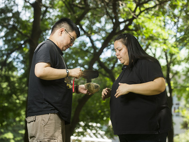 Two Indigenous community members participating in a smudge ceremony