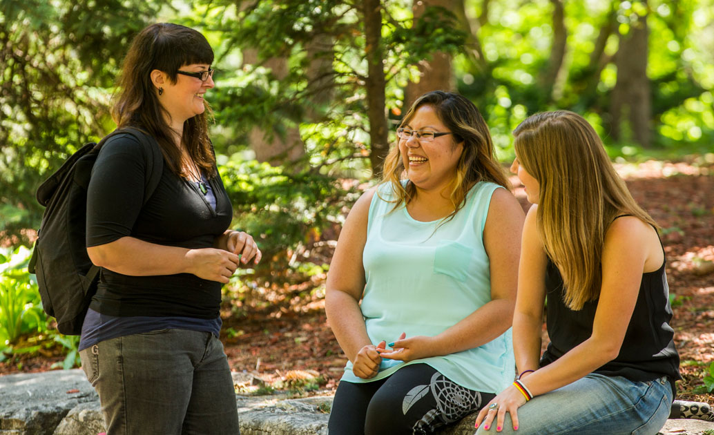 3 students conversing in a garden setting
