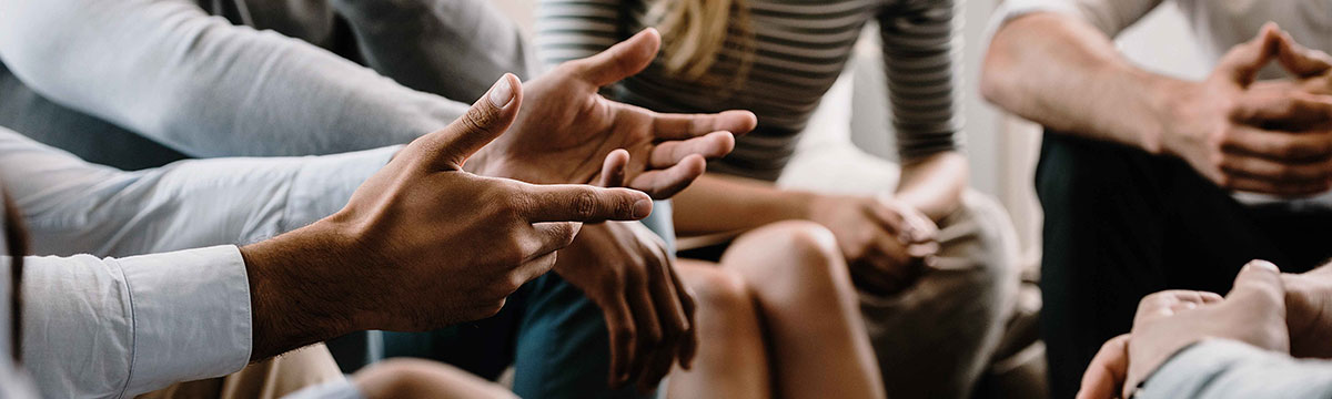 A group of people sitting in his circle with focus on their hands