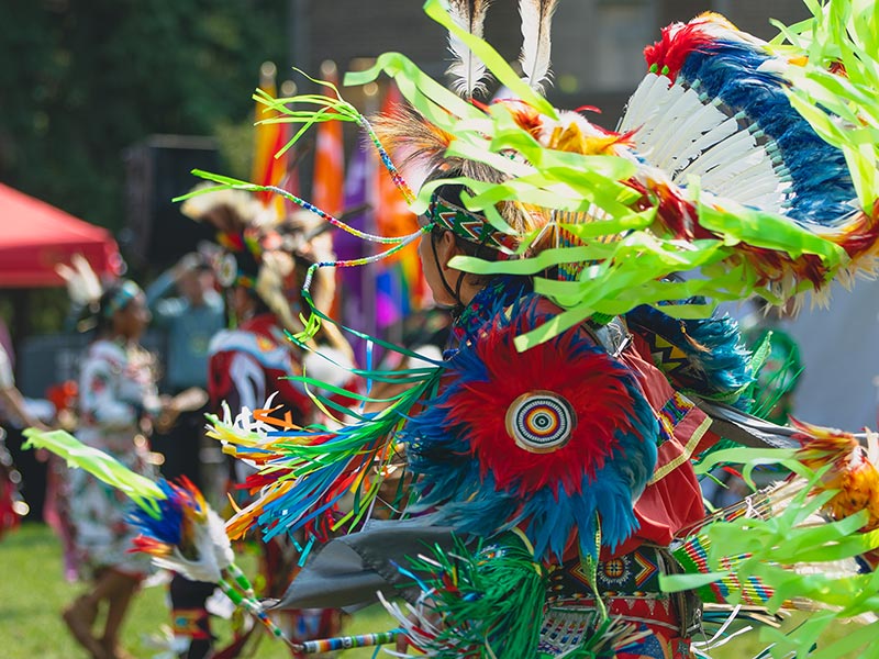A person in regalia dancing at the pow wow.