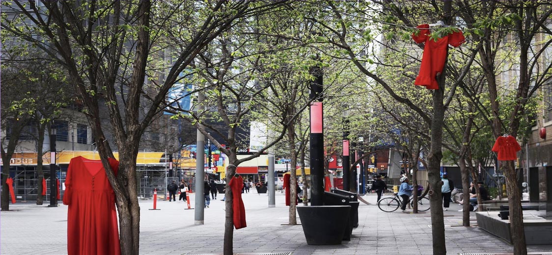A row of trees with red dresses hanging in them.