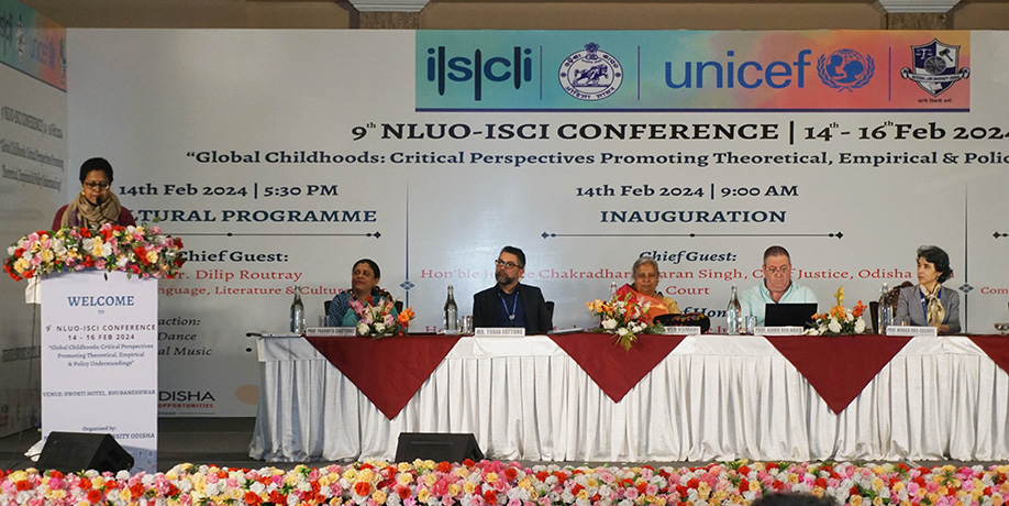 People sit at a decorated table on a stage during the awards ceremony at an ISCI conference