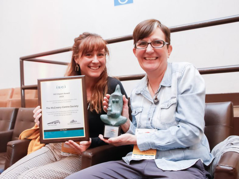 Two members of The McCreary Centre Society holding up the ISCI Impact Award
