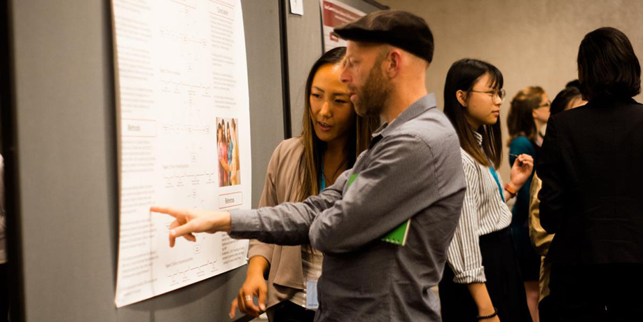 Two conference goers pointing at a poster at the Montreal ISCI conference 