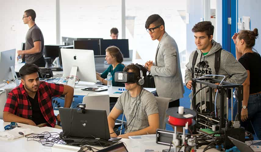 students gathered around someone wearing a VR headset