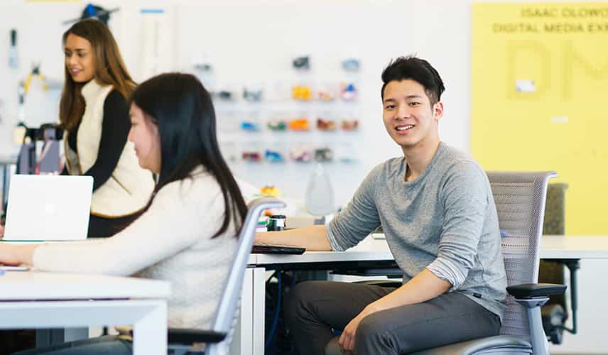 an Asian male student smiling in a classroom environment