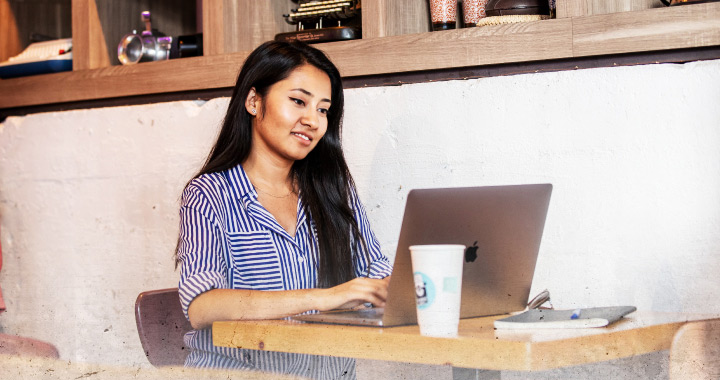 Happy student typing and looking at a laptop screen