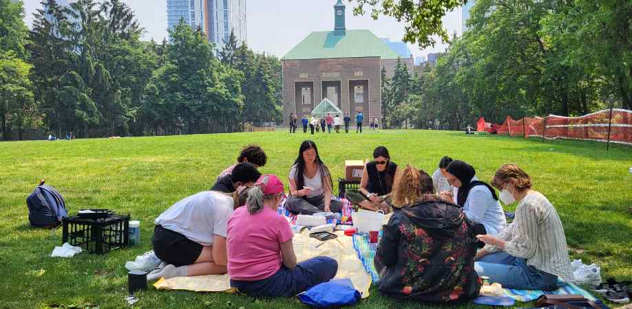 Graduate students sitting in Kerr Hall Quad and painting rocks