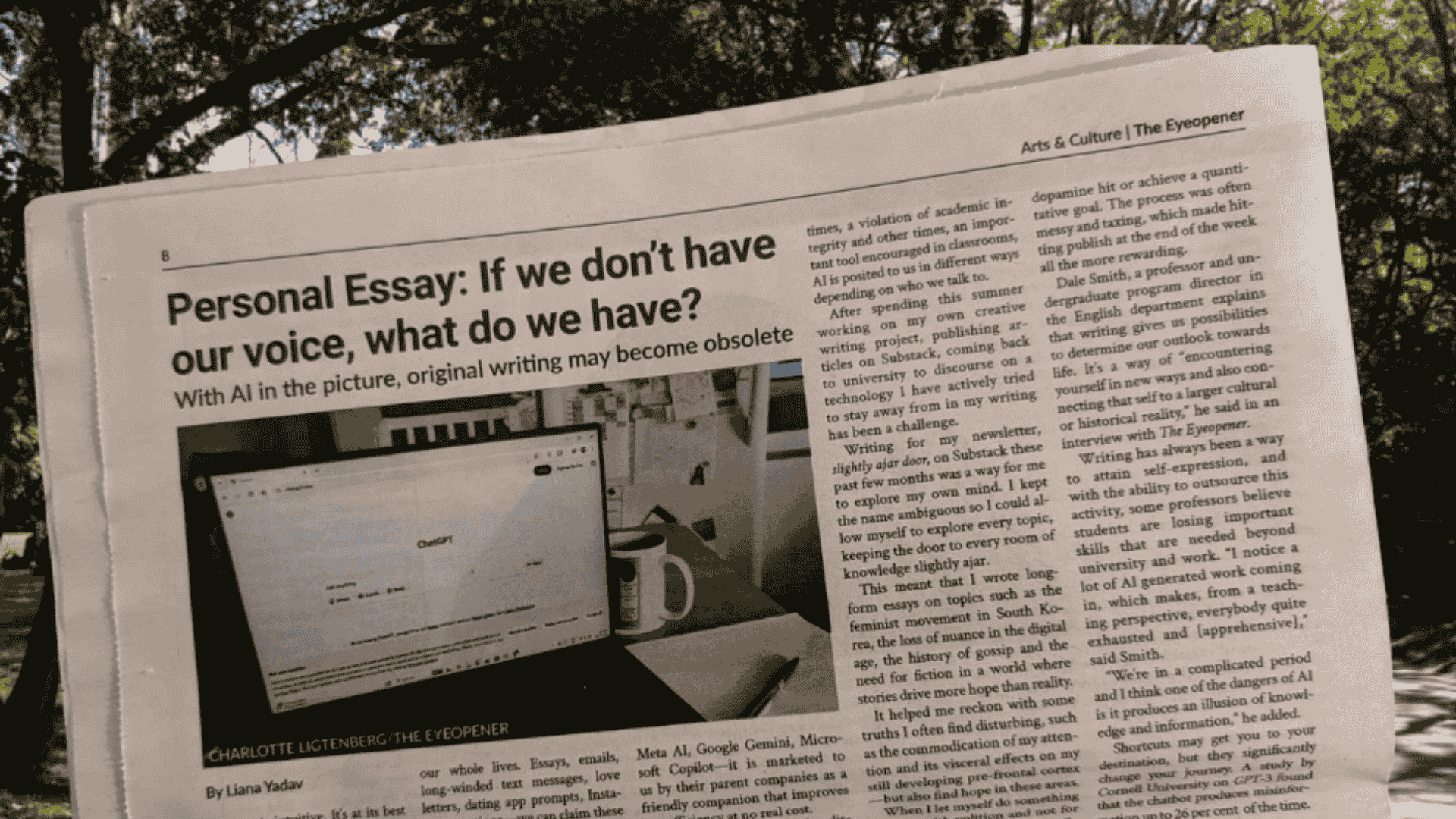 Student holding open a newspaper page in the university campus quad