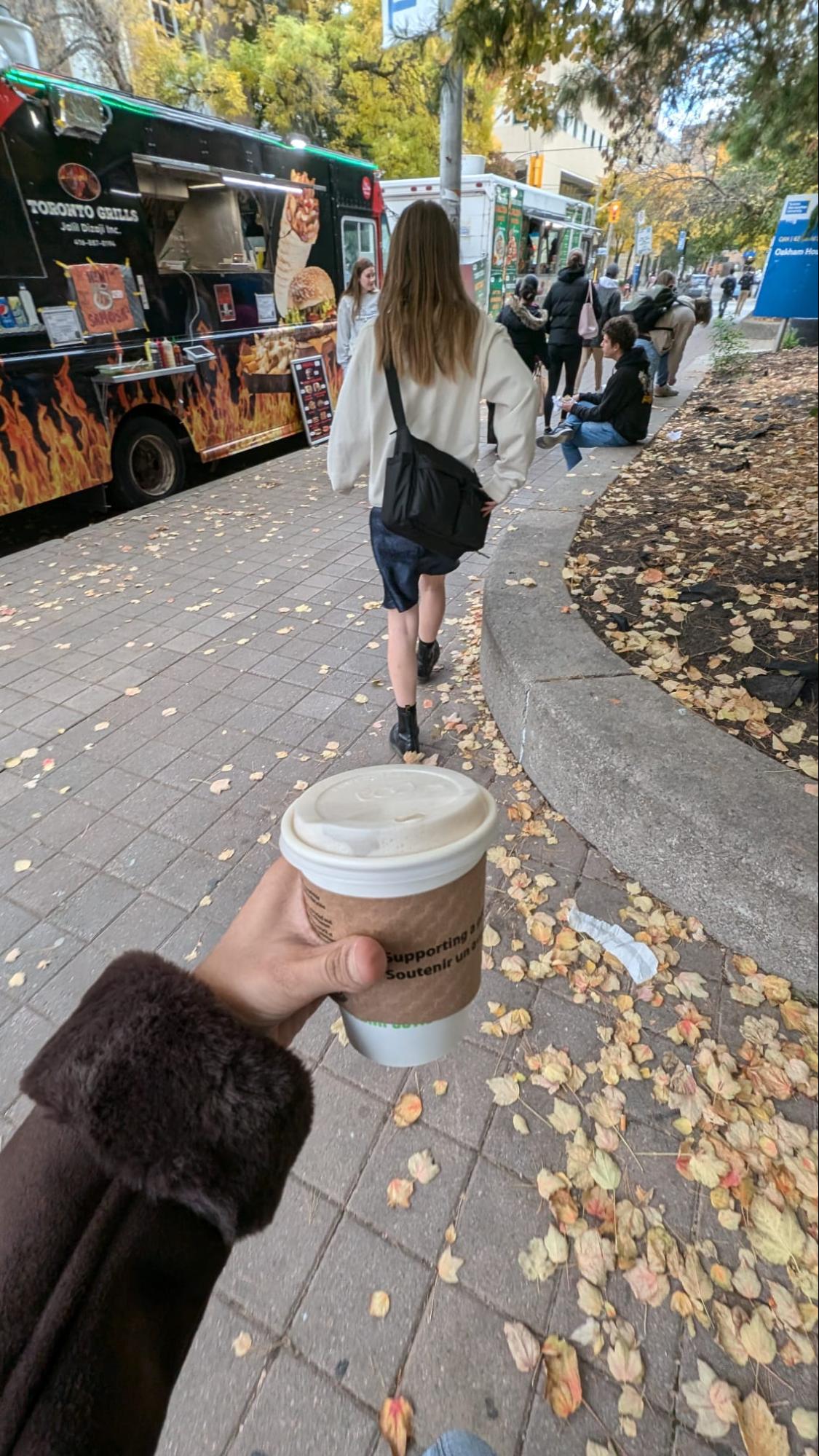 Hand holding a coffee cup while walking to school