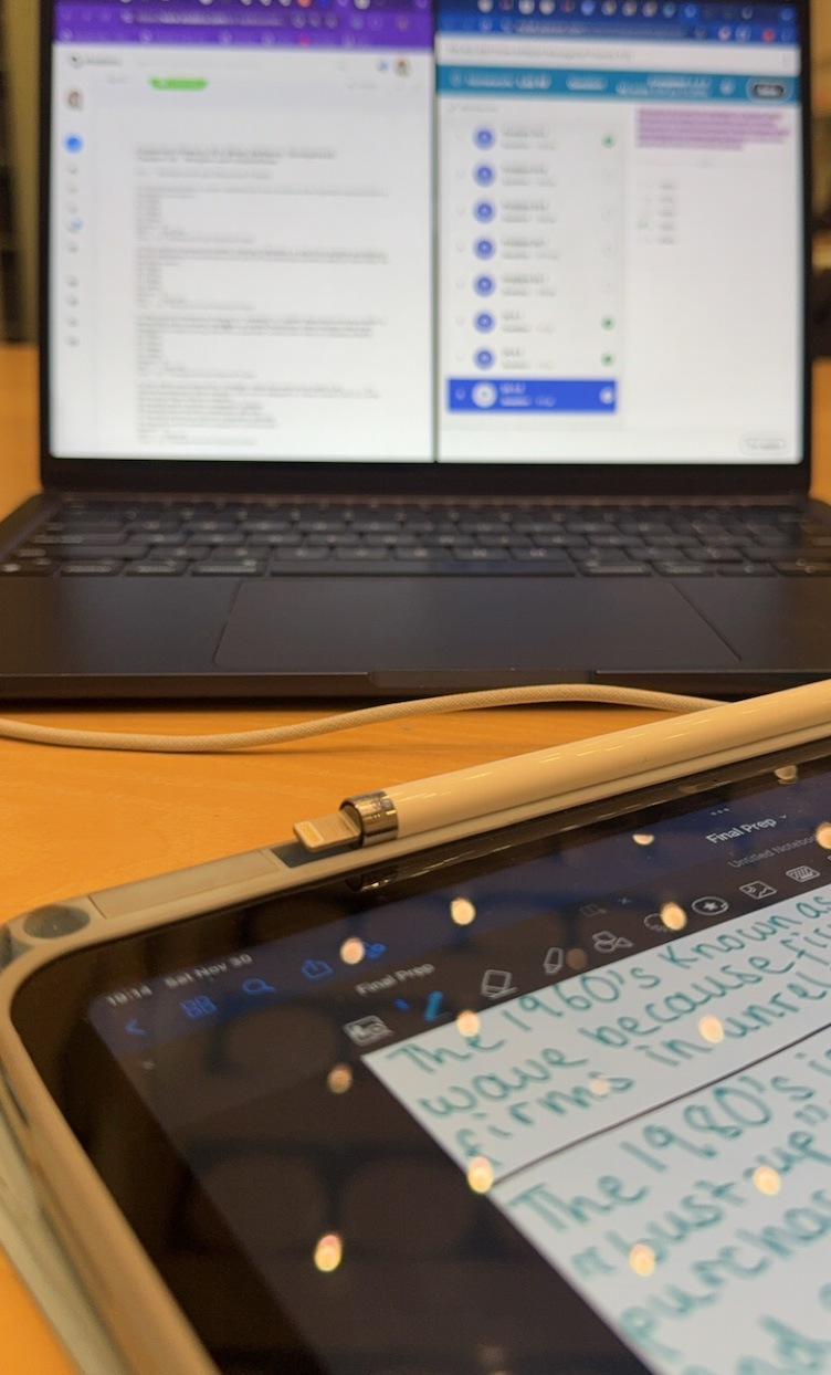 student studying with ipad and laptop on a desk
