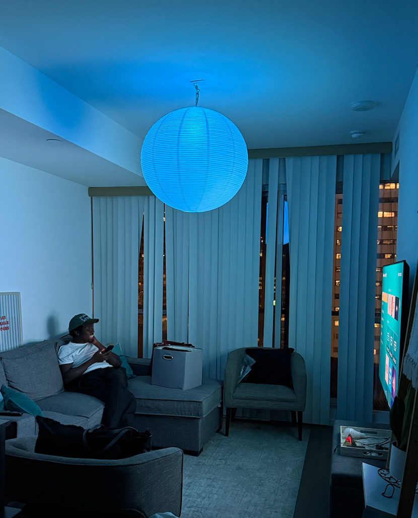 Person relaxing in living room with blue ambient lighting from spherical paper lantern