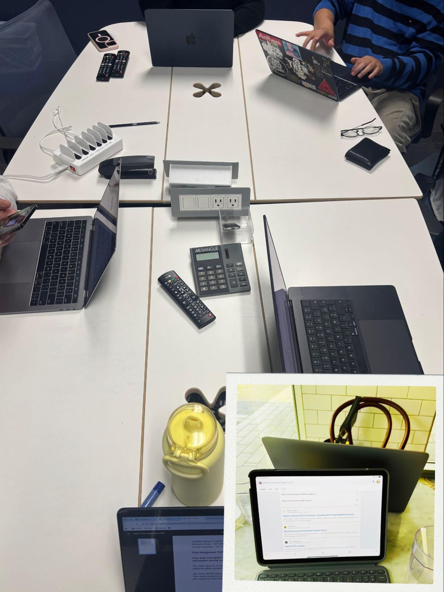 Overhead view of collaborative workspace with multiple laptops, tablets and phones