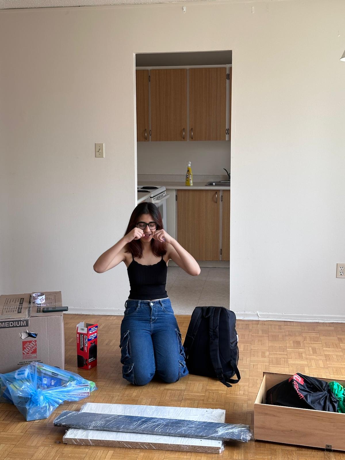 Student in an apartment surrounded with moving boxes
