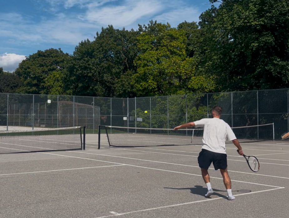 Person playing tennis on an outdoor court.