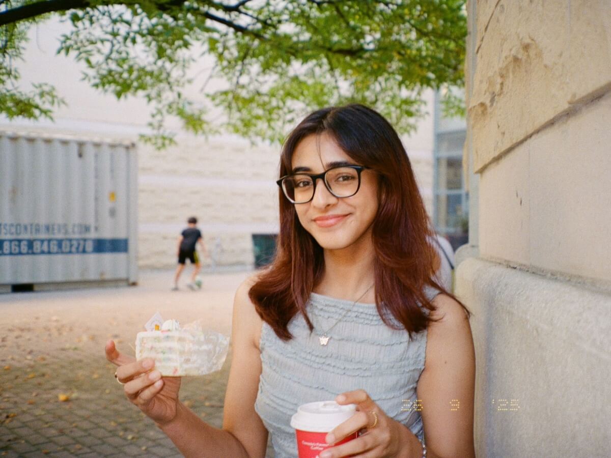Student posing with coffee and cake slice in the TMU campus quad