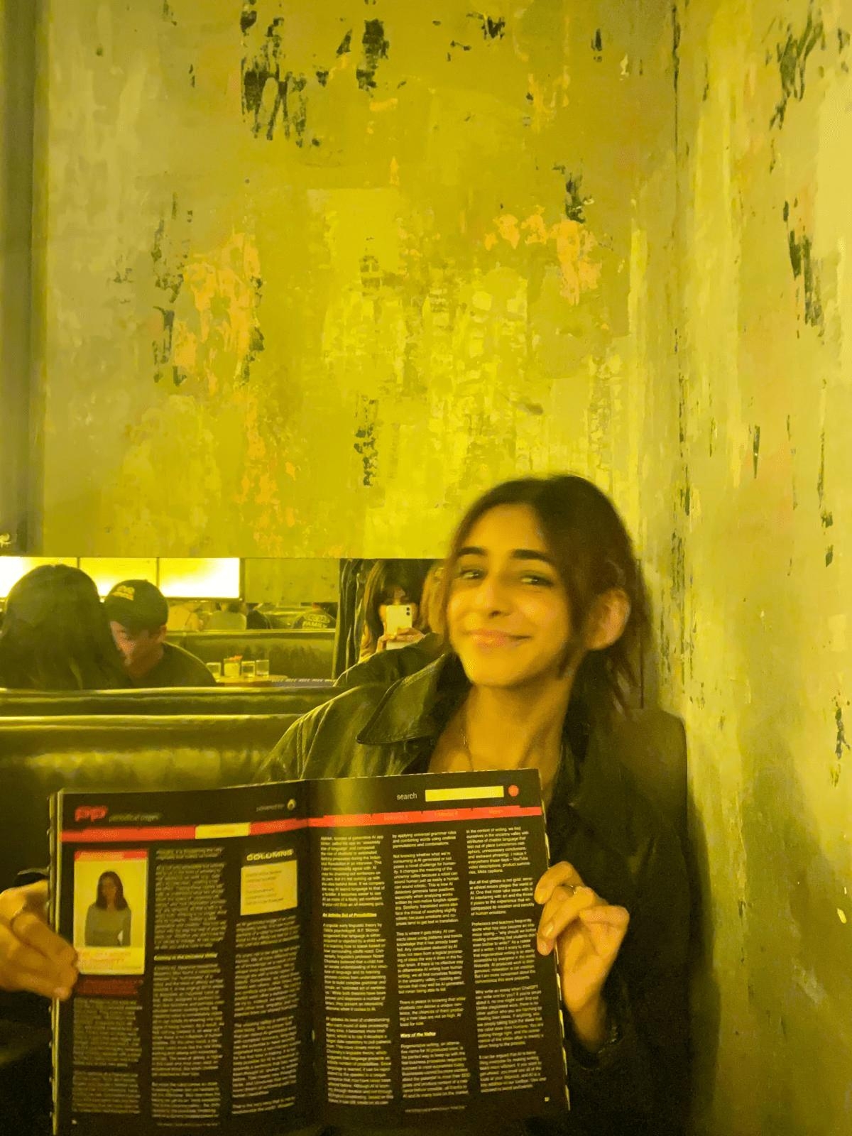 Student posing with TMU publication at launch party