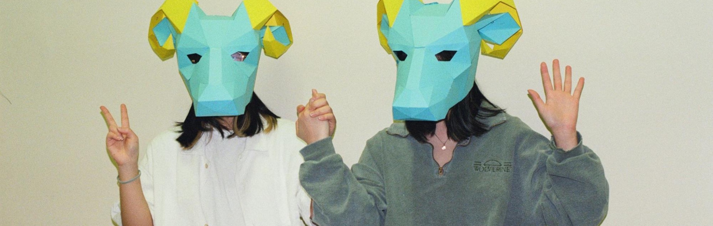 two friends wearing ram masks and holding hands.