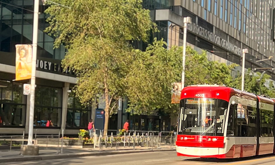 A streetcar is passing through Dundas Street, near Ted Rogers School of Management.