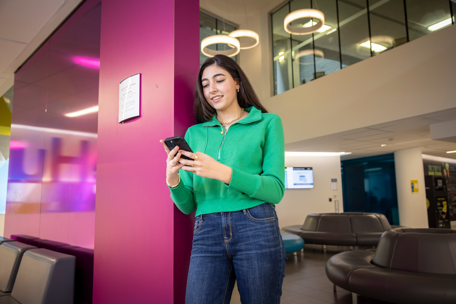 A female student looking at her phone at the service hub