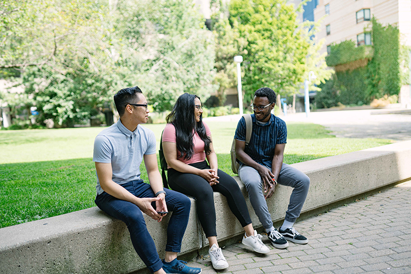Three students sitting outside of the Ryerson quad