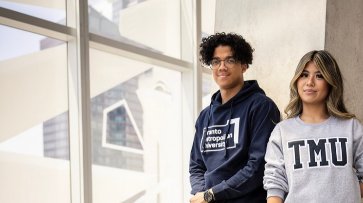 Sign up for the newsletter. Two TMU students smiling at the camera in the Student Learning Centre.