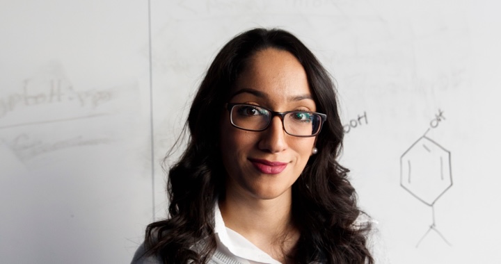 Student standing in front of a white board with science models drawn on