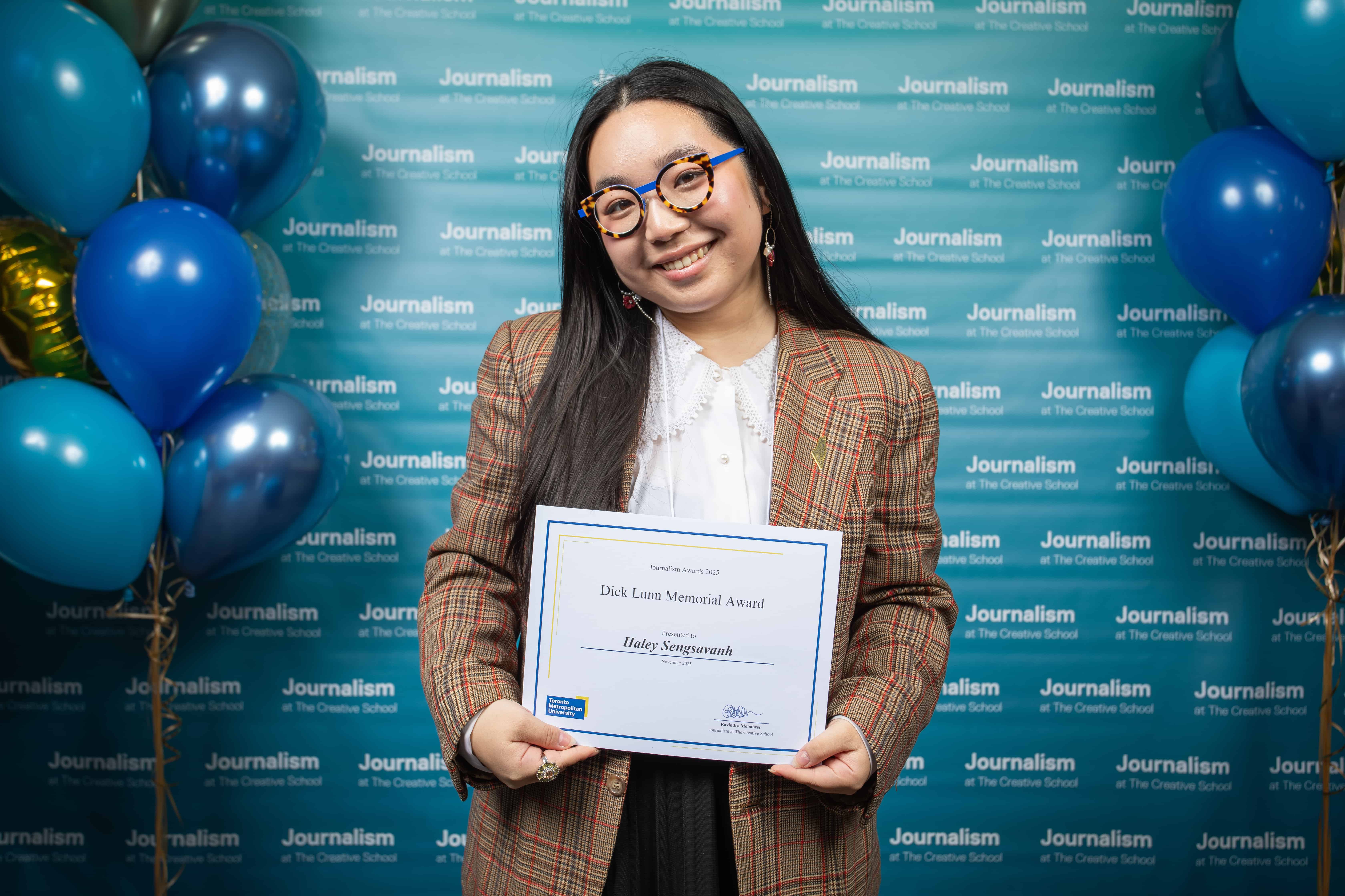 Photo of a person holding their certificate at Journalism School Award ceremony
