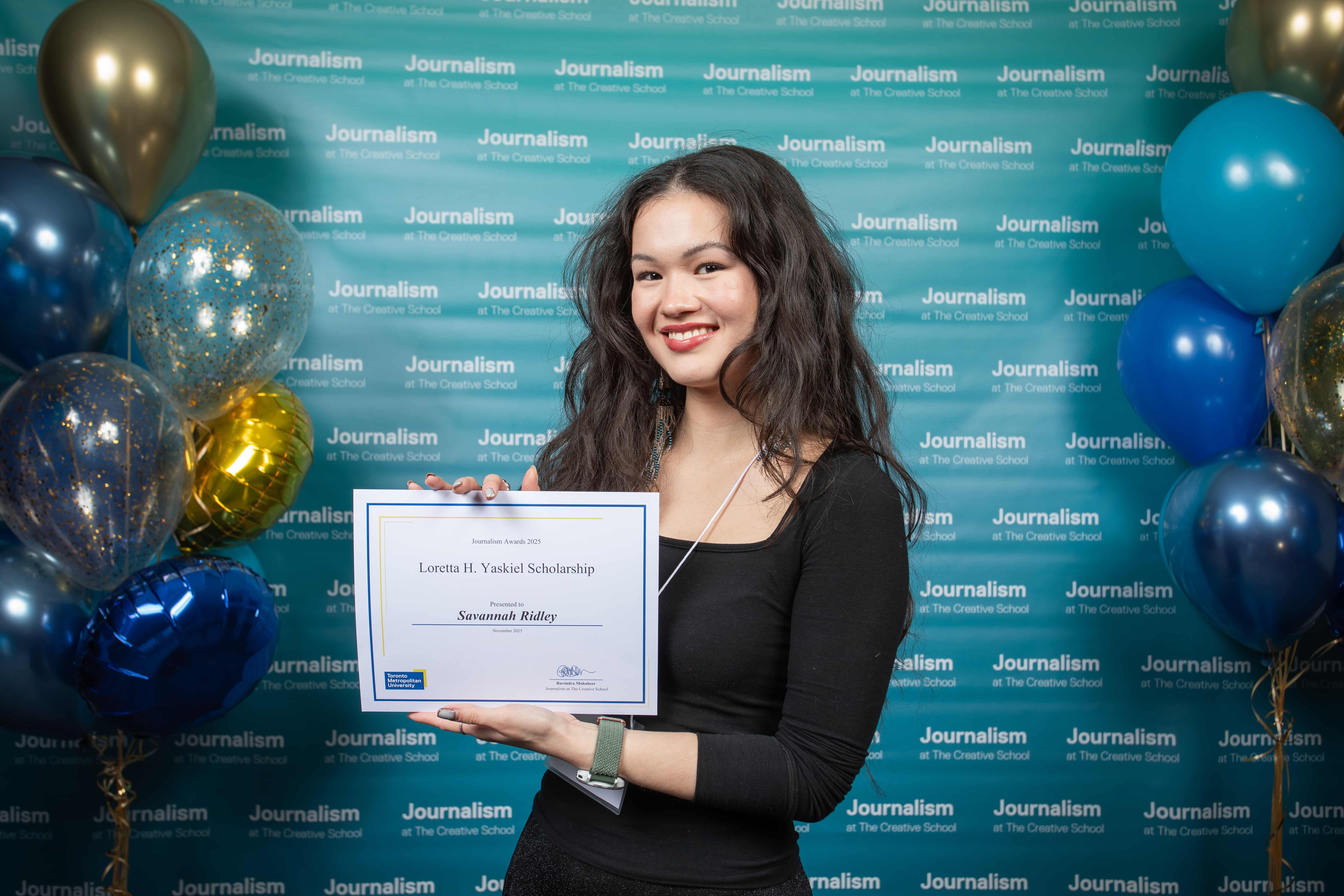 Photo of a person holding their certificate at Journalism School Award ceremony