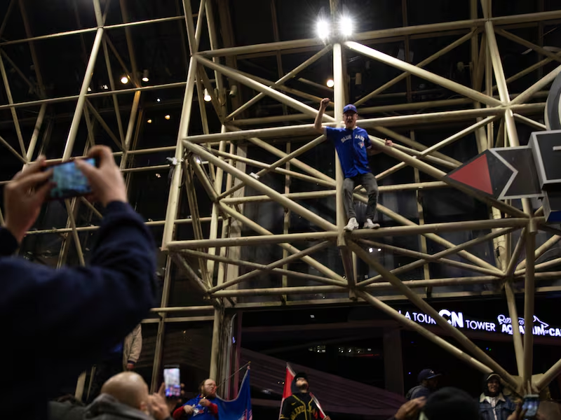 A man climbs scaffolding while a person takes their photo.