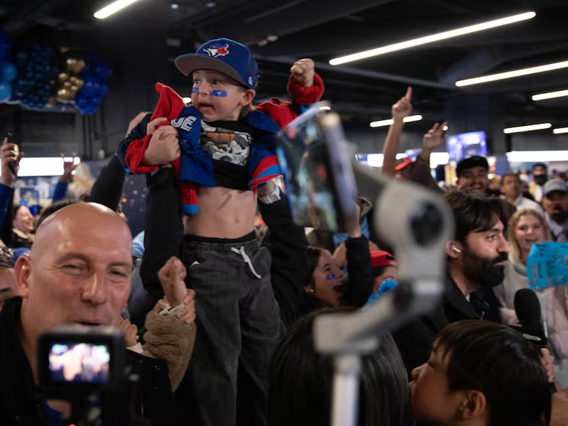 A child is raised up as people cheer around them.