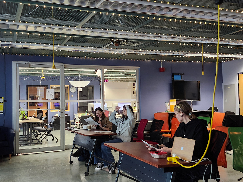 Three students sat at tables discuss in class