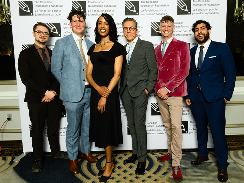 Masih Khalatbari stands next to a six people in front of a backdrop with the Canadian Journalism Foundation logo. 