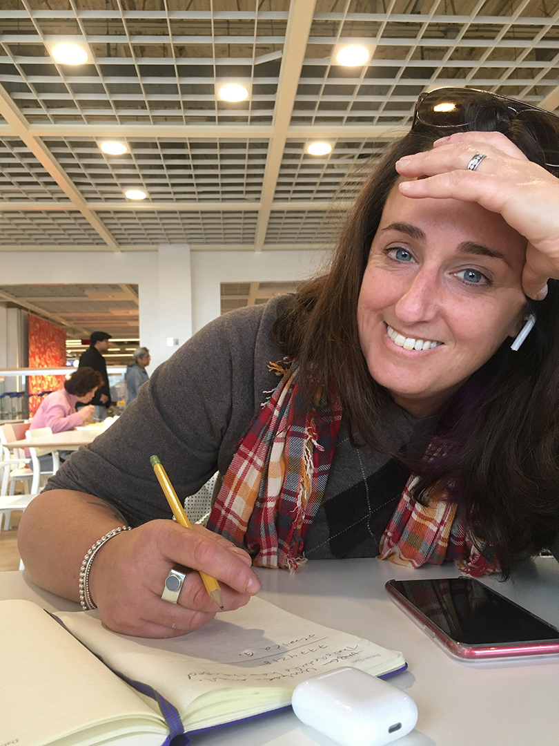 Alum Kathleen Goldhar writing at a table